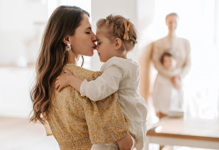 Foto familiar de una madre besando la frente de su hija
